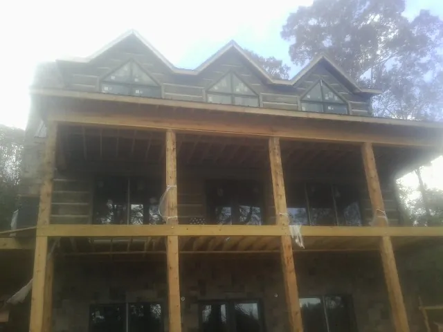Dormers and porch framing on a large log home under construction — Roof Coating work by our crew in Overbrook