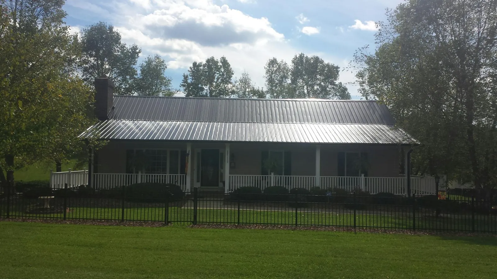 Gray metal roof on a brick ranch with a full width front porch — Gutter Guard Installation work by our crew in Overbrook